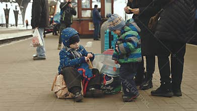 Lviv, Ukraine - March 15, 2022: Portrait of two little kids refugee from Ukraine playing at the railway station. War