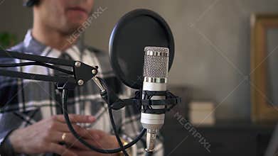 Closeup view of male speaker speaking and recording podcast in front of microphone in studio spbd.