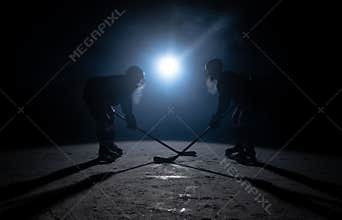 Silhouettes of two hockey players colliding with sticks on the ice arena. Rivalry of two male athletes in uniform