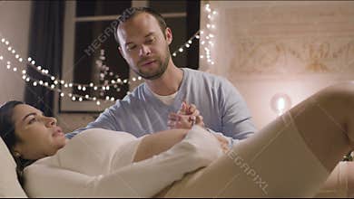 Husband sitting next to pregnant woman and stroking belly
