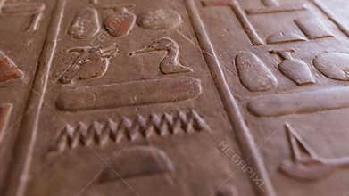 Antique stone wall with carved ancient Egyptian