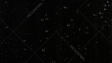 Closeup water rainfall, rain drops falling on window glass over black background
