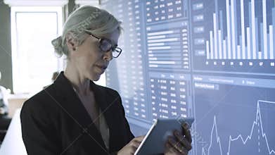 Middle-aged content businesswoman using tablet and standing