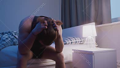 Young caucasian man sitting on the bed and pulling his hair. Insomnia problem, mental disorder or depression
