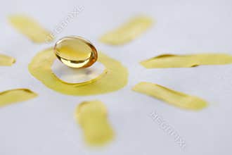 Yellow transparent vitamin D pill lying on drawn sun closeup