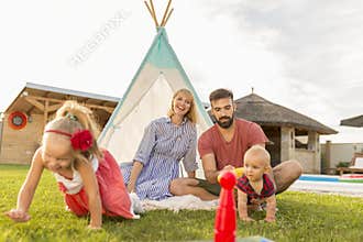 Parents playing with children while camping in the backyard