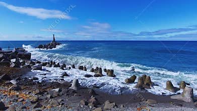 Rocky beach with breakwaters of azure sea with foamy waves