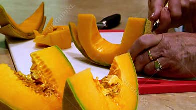 Cantaloupe muskmelon wedges are cut into sections with two knives.