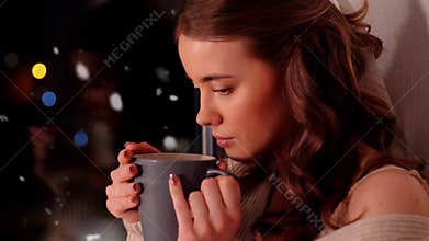 Woman with coffee or tea cup on windowsill at home