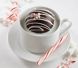 Hot cocoa bomb in cup of milk with peppermint stick