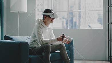 Smiling Asian guy in VR headset with controllers in hands