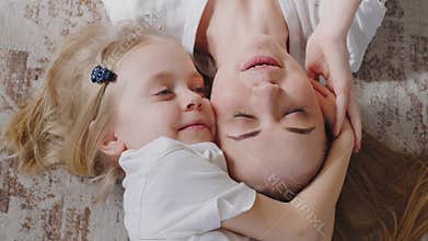 Top view little girl daughter child kid hugs embraces cuddles beloved adorable young blonde mother, family cheerful mom