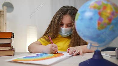 fun child kid in a mask draws a rainbow at home. stay at home coronavirus concept. girl kid in mask draws a rainbow at