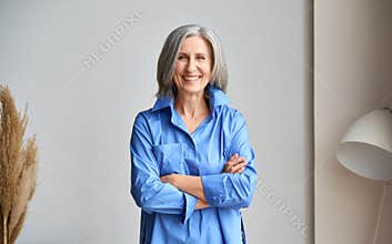 Senior laughing 60s woman portrait indoors looking at camera.