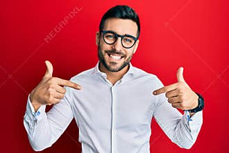 Young hispanic businessman wearing shirt and glasses looking confident with smile on face, pointing oneself with fingers proud and