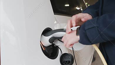 Woman connecting power supply to electric vehicle for charging and blocks car using smart watch.