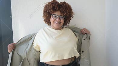 Beautiful happy smiling curvy plus size African black woman afro hair posing in beige t-shirt, jeans, stylish glasses on