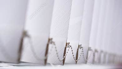 Big vertical modern venetian blind hangs on window in office room