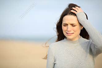Sad woman walking alone on the beach