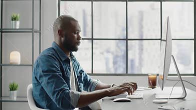 Black designer works on contemporary computer in office