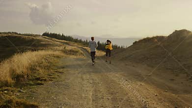 Athletes running on road in mountains. Couple doing cardio workout outdoor