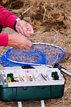 A fisherman binds fish hook.