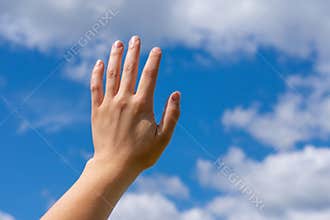 Sunlit female opened hand in gesture as touching heaven, blue summer sunlight. Metaphor of calmness, mercy and faith, support.