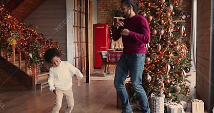 Energetic mixed race family dancing together in living room.