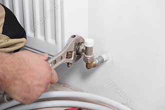 Plumber installing new steel hot water central heating radiator