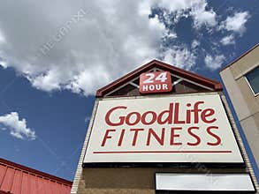 A sign on a building with Good Life Fitness and blue sky background. Goodlife Fitness is a 24 hr gym and health club.