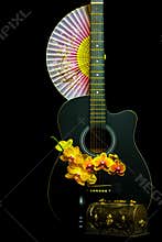 Still life scene with guitar, orchids and paper fan