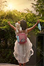 Girl with backpack, doll cat and masks, travel plan and carry-on.