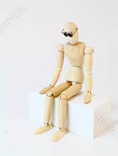 Wooden character sitting in deep thought