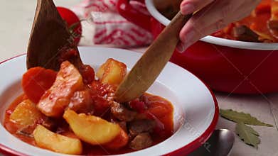 Beef stew with potatoes and carrots in tomato sauce in white plate.