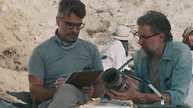 Male archaeologists examining ancient vase