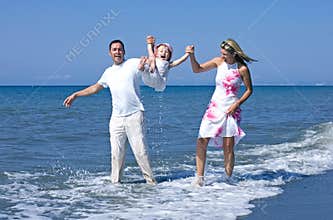 Young family playing with daughter on beach in Spain