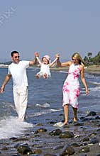 Young family playing with daughter on beach in Spain