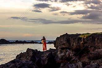 A young woman standing on the shore in the beautiful Carlsmith Beach Park in Hilo, Hawaii