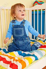 Happy toddler sitting in the baby cot