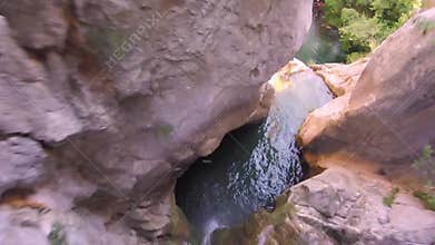 Unrecognizable man plunging off a dangerous canyon cliff into river basin