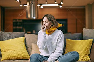 Unhealthy female cover mouth with hand while coughing, suffer grippe or bronchitis chronic disease sitting on couch