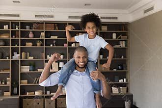 Little son sits on strong fathers shoulders demonstrate biceps strength