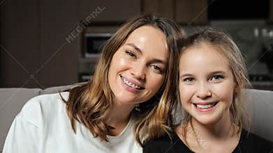Mother and daughter smile widely looking in camera at home
