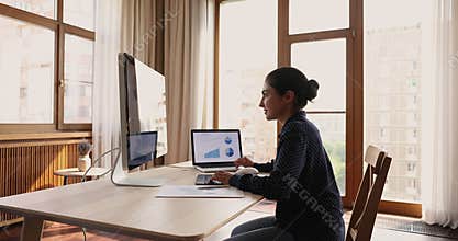 Indian female trader analyze charts and graphs shown on computers