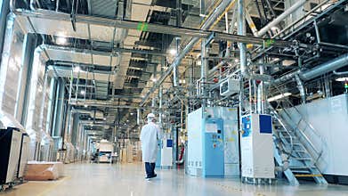 Factory employee in a lab coat is doing an inspection