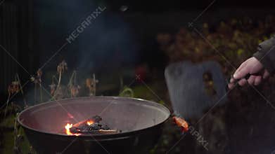 Close-up of a hand fanning a fire