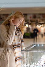 Young woman looking at the shop showcase and jewelry to look at it closer