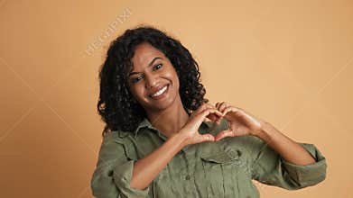 The beautiful young black woman shows her heart sign and smiles.