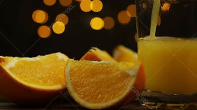 Orange juice is poured into a tall glass with ice on a black background
