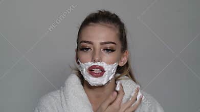 Beauty woman with foam on the face and a razor blade. Trans gender concept. Woman shaving face.